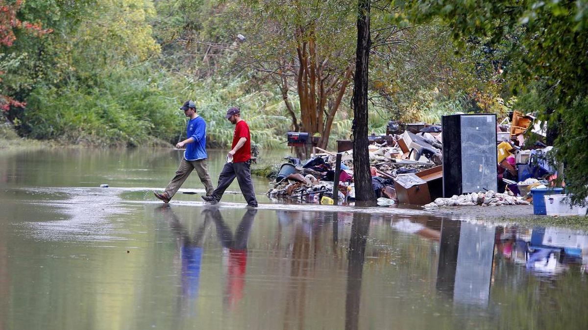 Ricky Spitz and Riley Maxwell walk through flood waters on Timberlane Drive in Columbia in the wake of the October rainfall.
