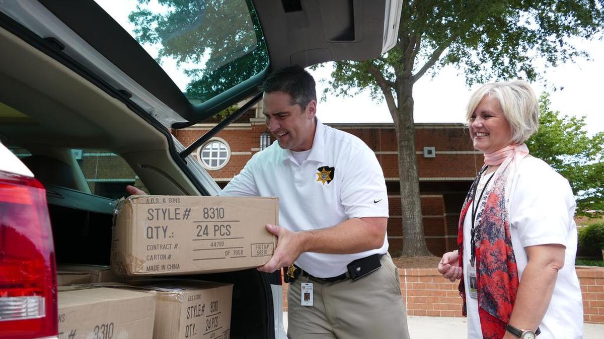 
York County Sheriff’s Office spokesman Trent Faris loads backpacks and school supplies for Kelly McKinney of Fort Mill schools. The Sheriff’s Foundation of York County purchased 288 backpacks and 288 school supply kits to be divvied up between the four school districts in York County and given to needy students and families. 
