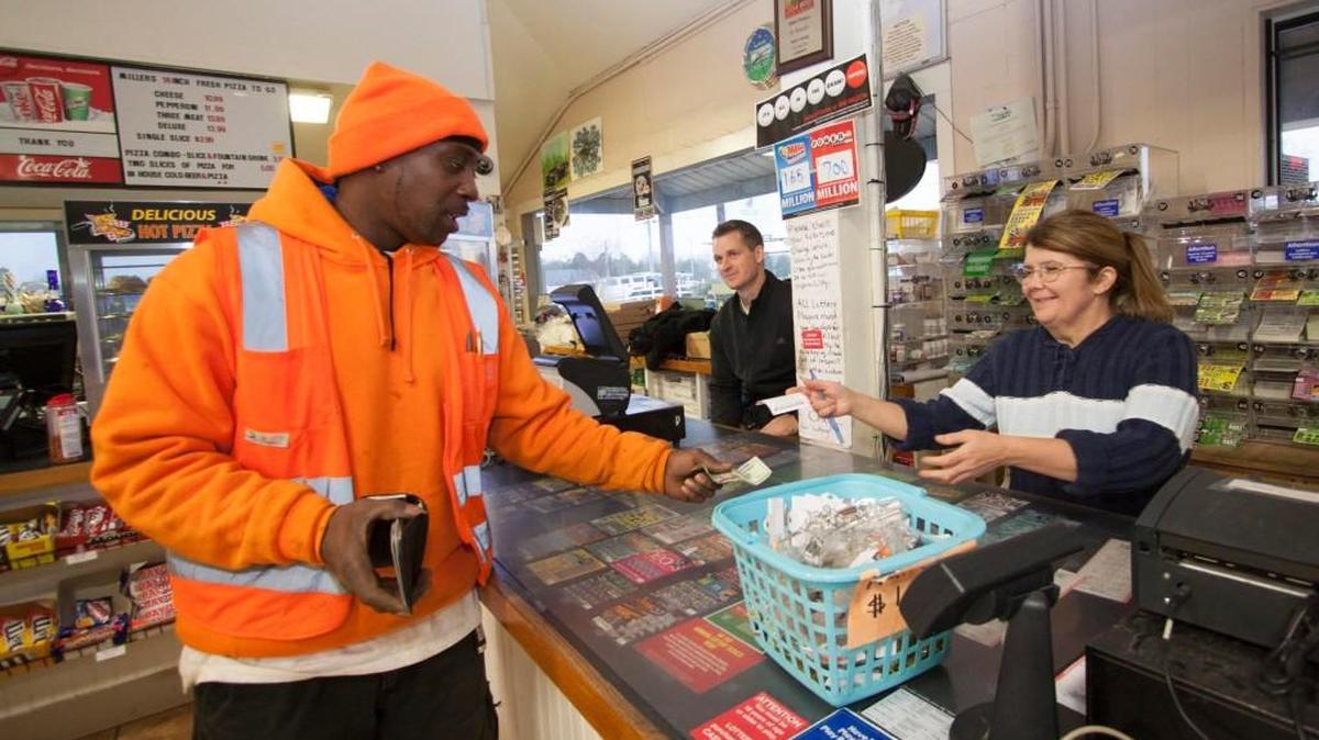 Randy Blount buys a Powerball ticket as Patricia Pasternak takes his money Friday at Miller’s Produce in Fort Mill. Store manager Matt Miller, middle, says ticket sales have at least doubled as the jackpot reached nearly $700 million.