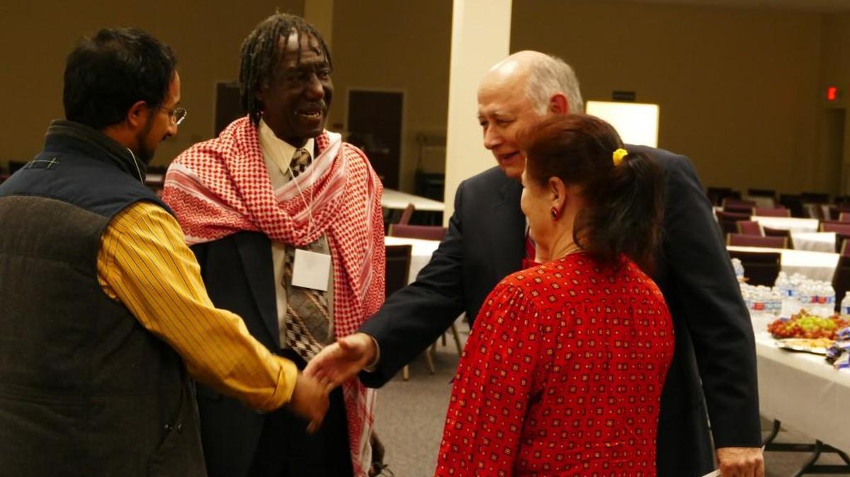 Reaching out across faiths, Fahad Saad, an international student at Winthrop University from Saudi Arabia, shakes hands with Will Reed from First Presbyterian Church of Rock Hill. Saad stands with James “Jumah” Moore, executive director of the Islamic Center of South Carolina, and Dawn Abell with the Committee for Racial and Religious Reconciliation.