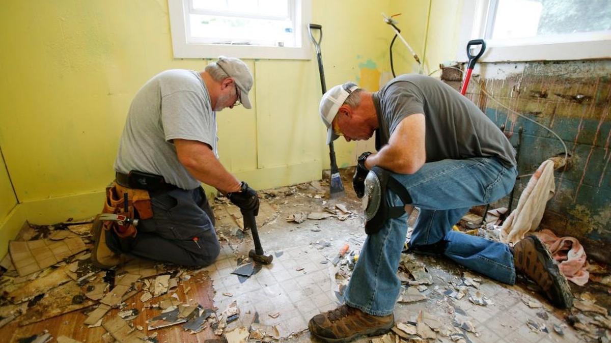 
Habitat for Humanity of York County and a group of Comporium employees and members of the Comporium Pioneer Club work Thursday to complete critical home repairs for five families in the Paradise neighborhood of Fort Mill. Ken Hargett, left, and Tim Hallman work to remove old floor covering from the kitchen in a house on Avery Street. The entire kitchen is being repaired.
