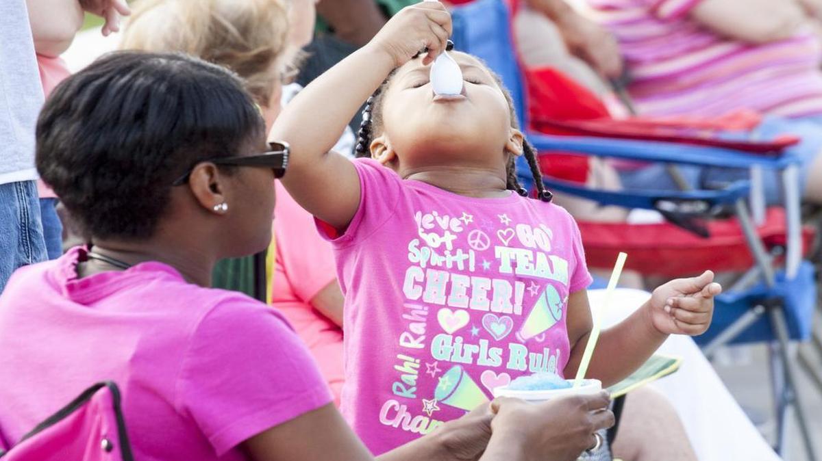 
Kyndall Hood, 4, enjoys a blue slushie Friday evening at the Red Rose Festival in downtown Lancaster, while her mom, Brandi Duncan, left, listens to a band.
