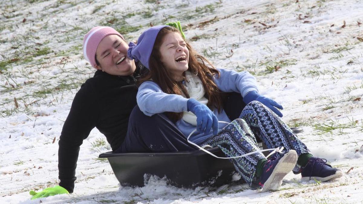 Julie Montes, left, and Gaby Montes sled down a hill Saturday.