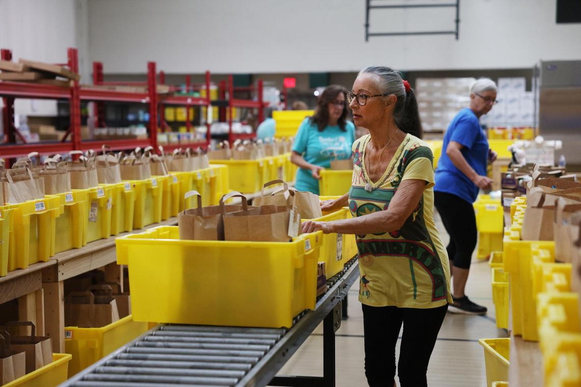 Linda Greenwald moves grocery items down to be loaded into cars Monday at HOPE.