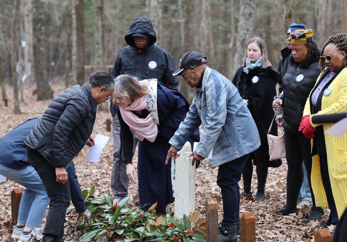 Descendants of enslaved people at Historic Brattonsville lay a gravesite blanket at the grave marker of Watt, an enslaved person who lived at the plantation in the 1800s.