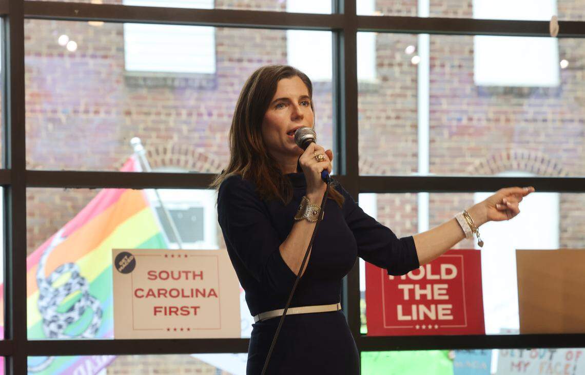 Republican candidate for South Carolina governor Nancy Mace talks to a crowd at Hoppin' in Rock Hill Monday as protesters walk by carrying flags and signs outside.