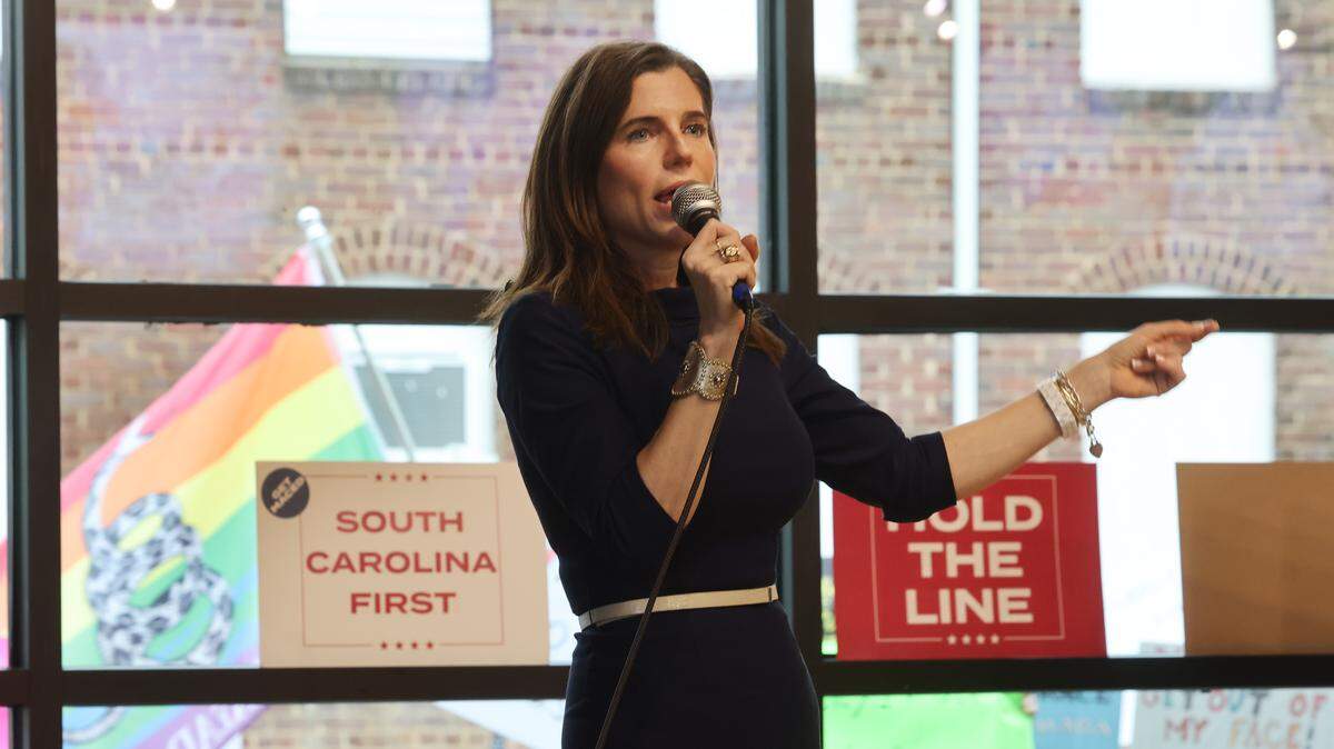 Republican candidate running for South Carolina governor, Nancy Mace, talks to a crowd at Hoppin' in Rock Hill Monday as protesters walk by carrying flags and signs outside.