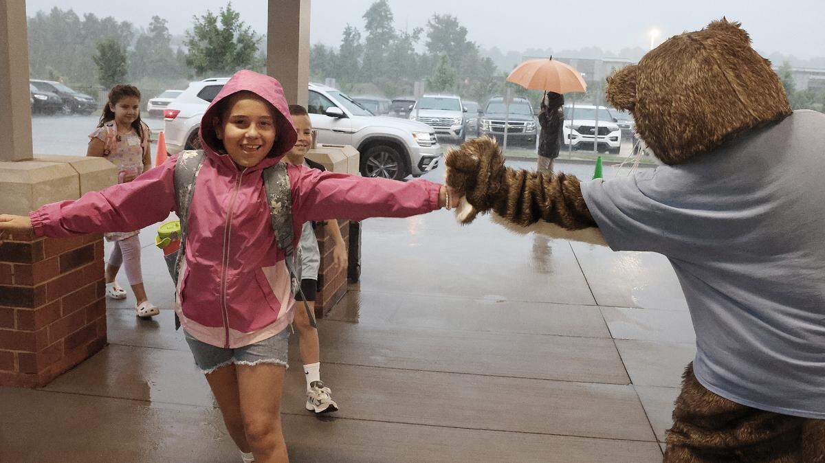 A child gives Ollie the Otter a high-five at the drop-off line at River Trail Elementary School in Fort Mill Thursday. Schools started in Fort Mill and Rock Hill Thursday.