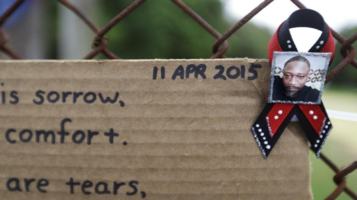 
A ribbon with the image of Walter Scott is affixed to the fence with a message at the scene where Scott was fatally shot by a white police officer after he fled a traffic sto on April 12, 2015, in North Charleston, S.C. The officer, Michael Thomas Slager, has been fired and charged with murder. 

