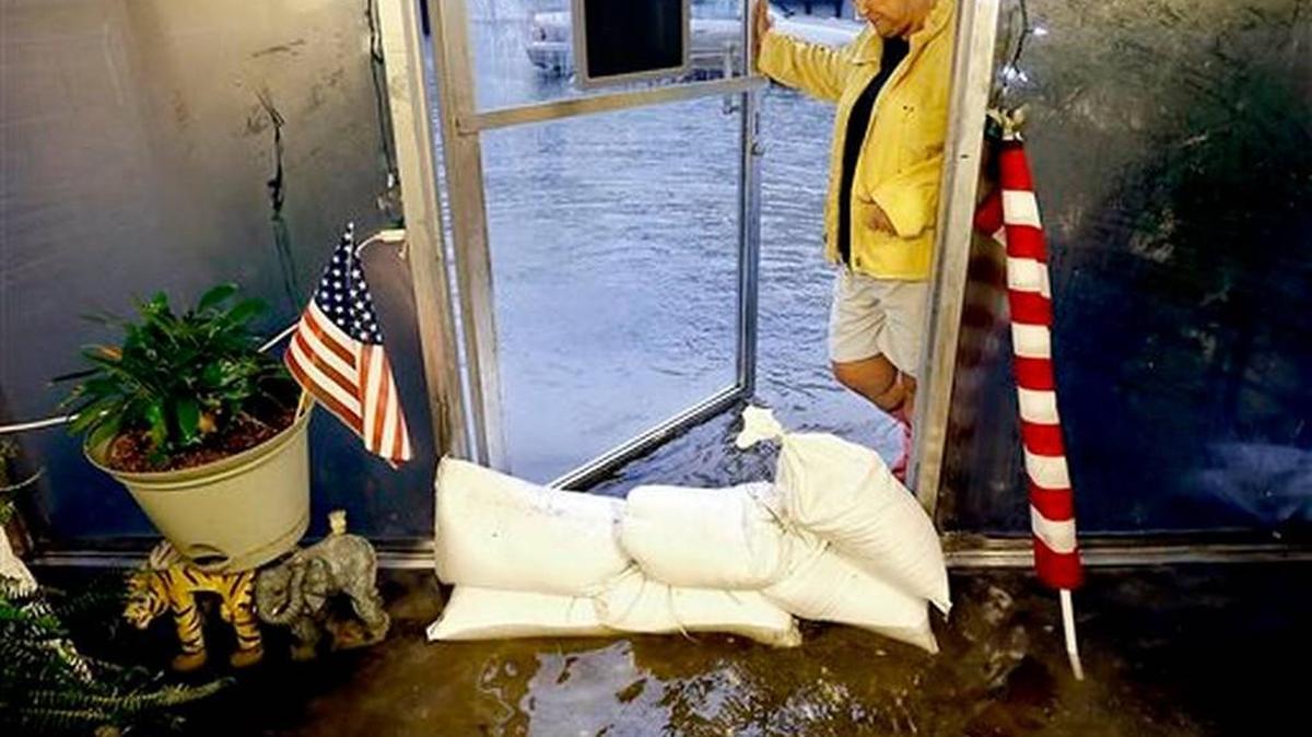 
Vivian Garvin, owner of Arrow Cleaners, watches as waves of floodwater, caused by vehicles driving, by splashes through the front door of her business, Saturday, Oct. 3, 2015 in Charleston, S.C. A flash flood warning was in effect in parts of South Carolina, where authorities shut down the Charleston peninsula to motorists.
