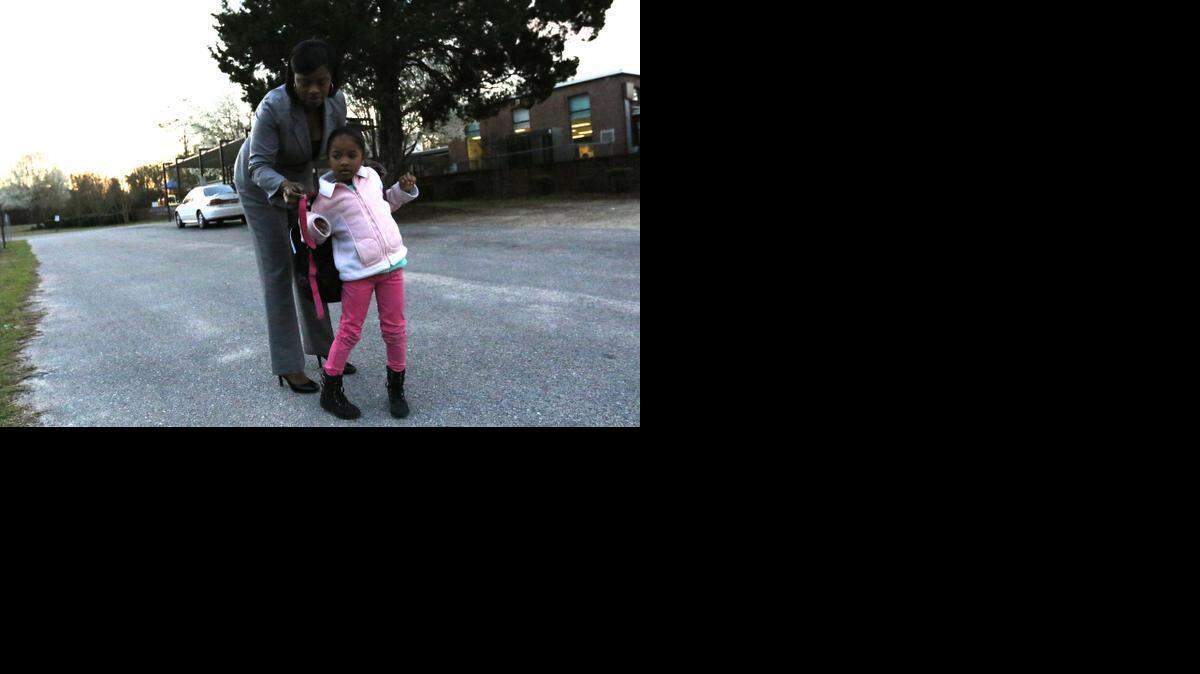 
Alisha Jackson puts a backpack on her daughter McKenzie before school at Gadsden Elementry. 
