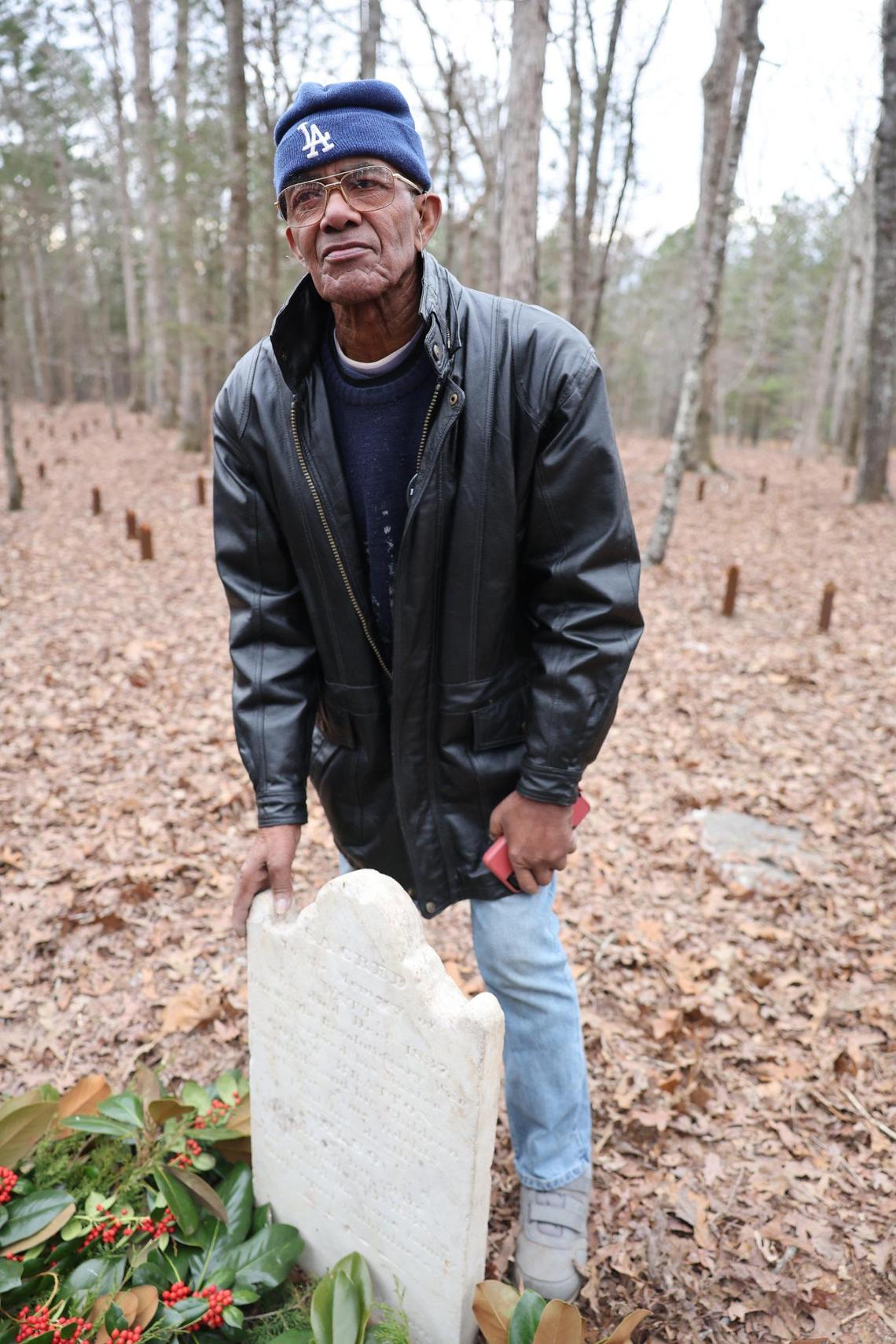 Wali Cathcart, a decendant of enslaved people at Historic Brattonsville, stands next to the grave site of Watt, a Revolutionary-era enslaved person at the plantation. Cathcart’s great-grandmother Lila was enslaved at Brattonsville.