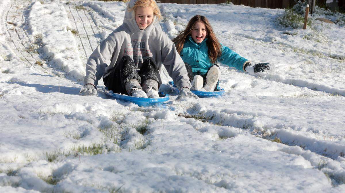 14-year-old Lila Hutto, left, and 10-year-old Laurel Hutto sled down a hill Saturday at their Rock Hill home.