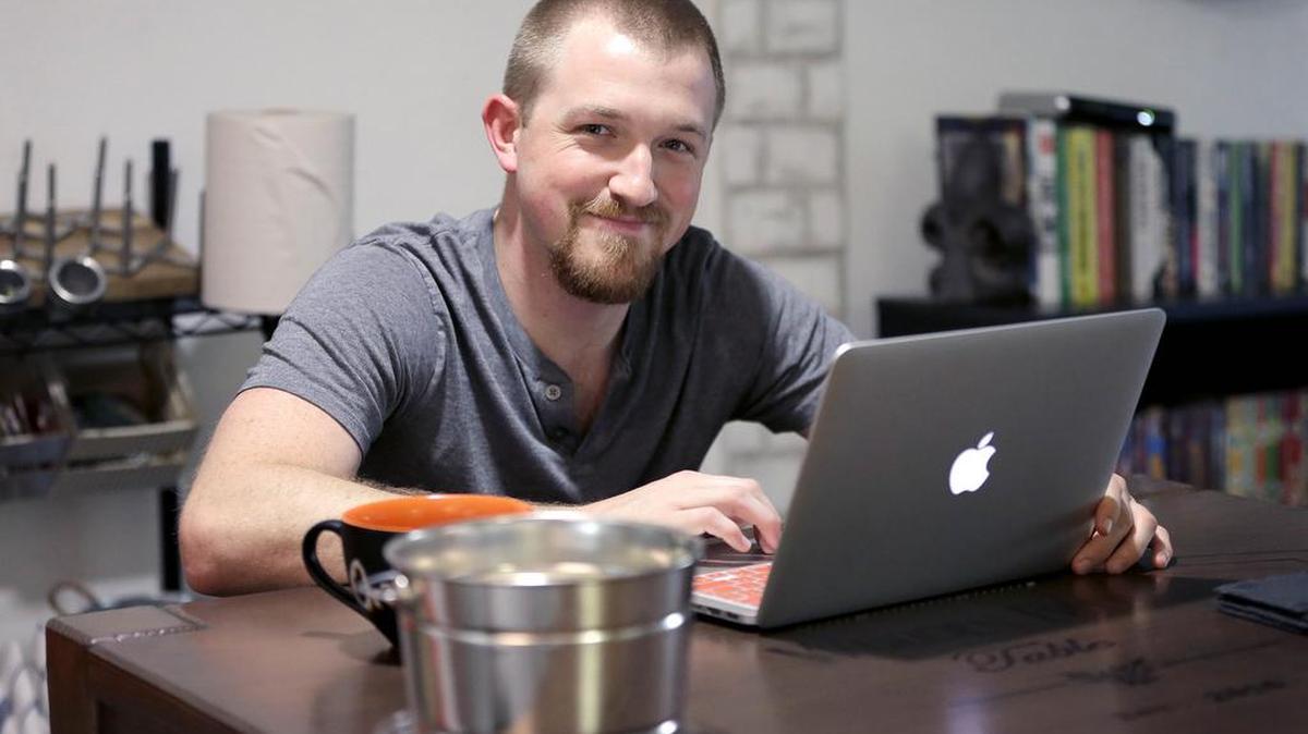 Mitchell Timme works from his laptop computer at his home in Phoenix. Timme said his wages have remained basically flat for the last few years while his cost of living has increased. Once everything is paid, he said, “there’s nothing left to save.”