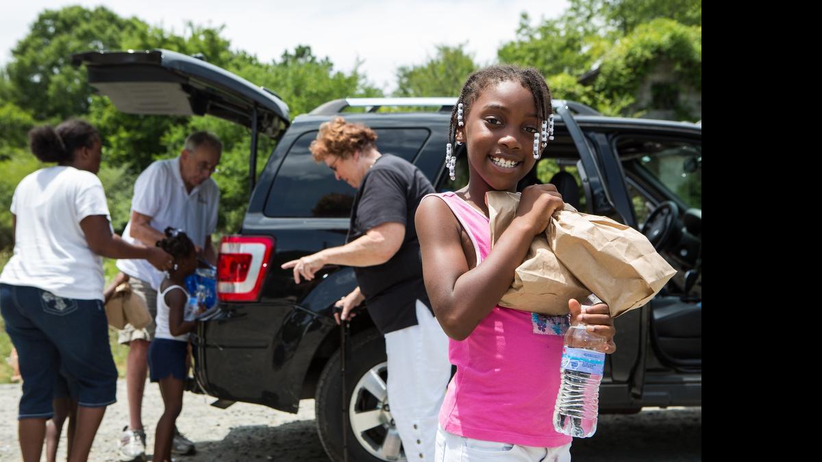 
Lacy Massey beams a smile after picking up a couple meals from Bob and Mary Ann Thomas as members of Lake Wylie Lutheran Church make their weekly meal deliveries to families in the Blackmon Road area on July 12.

