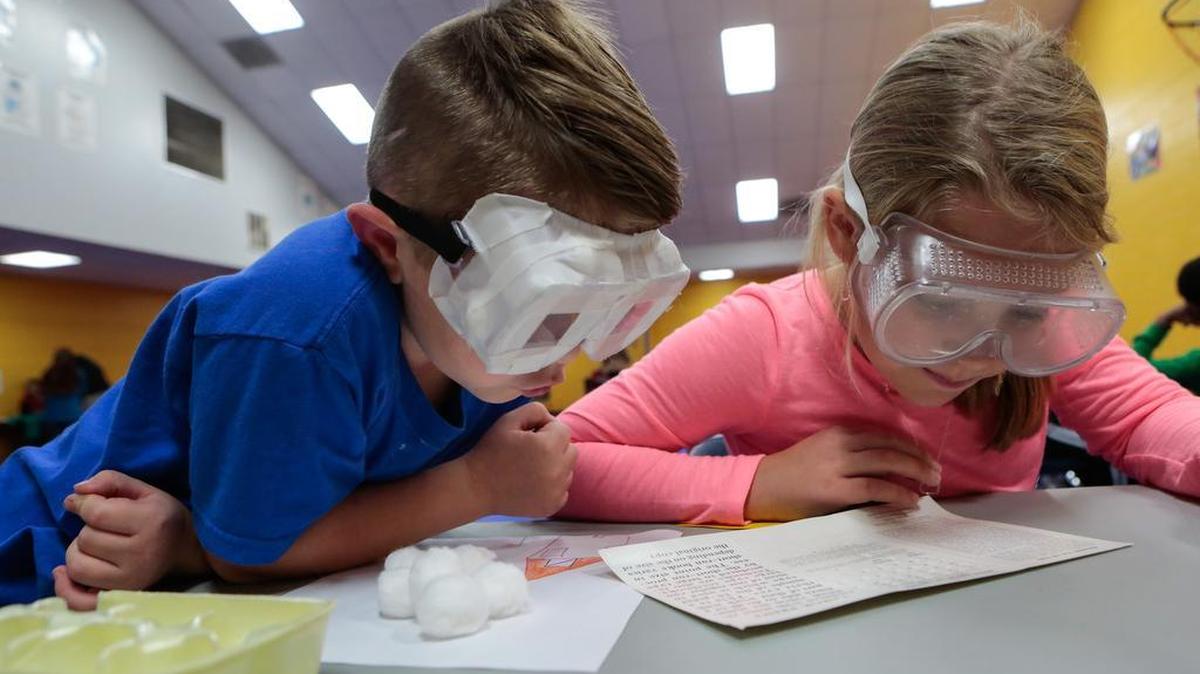 Levi Going and Josie Lancaster try to read while wearing goggles as third graders at Lewisville Elementary learn about disabilities during an anti-bullying campaign.