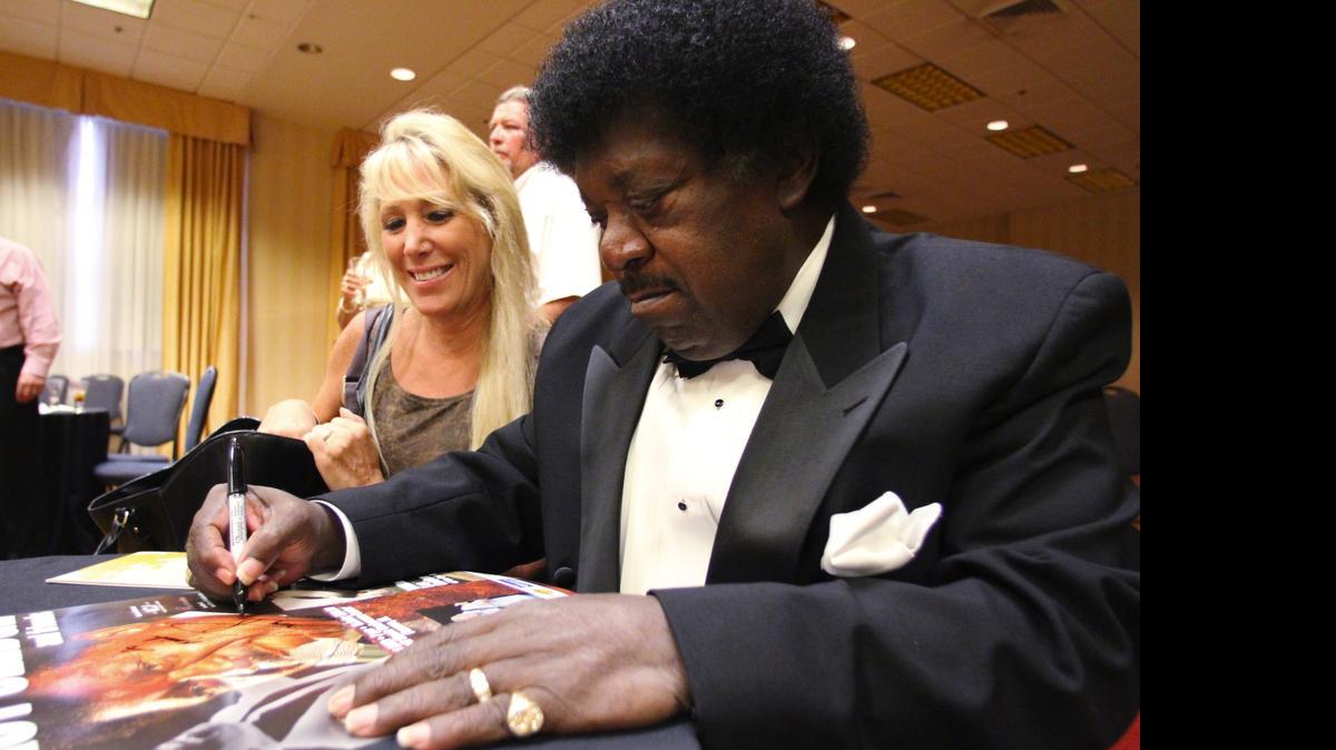
In this Aug. 20, 2013, photo, Tina Caruso, left, smiles as Percy Sledge signs a poster for her in Florence, Ala. Sledge, who soared from part-time singer and hospital orderly to lasting fame with his aching, forlorn performance on the classic "When a Man Loves a Woman," died April 14 in Louisiana. He was 74. (Allison Carter/The TimesDaily via AP) 
