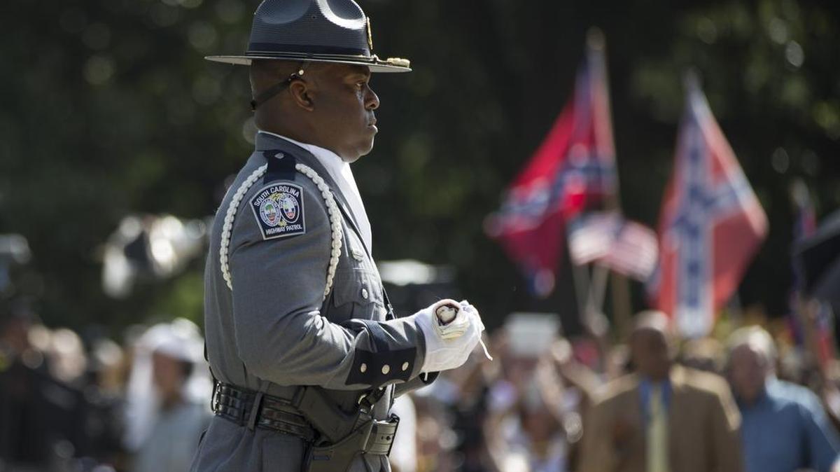 
A member of an honor guard from the South Carolina Highway patrol carries a Confederate battle flag as they remove it from the Capitol grounds Friday, July 10, 2015, in Columbia, S.C. The Confederate flag was lowered from the grounds of the South Carolina Statehouse to the cheers of thousands on Friday, ending its 54-year presence there and marking a stunning political reversal in a state where many thought the rebel banner would fly indefinitely.
