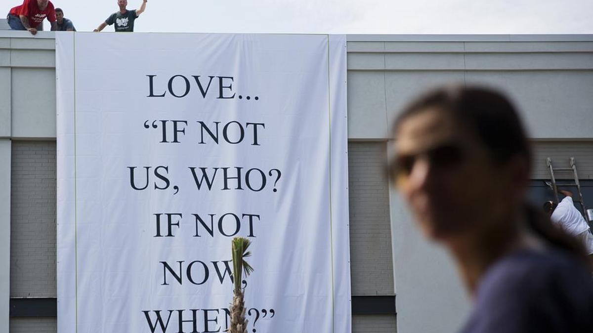 Days after the massacre, a worker hang a banner from a business near the Emanuel AME Church in Charleston.