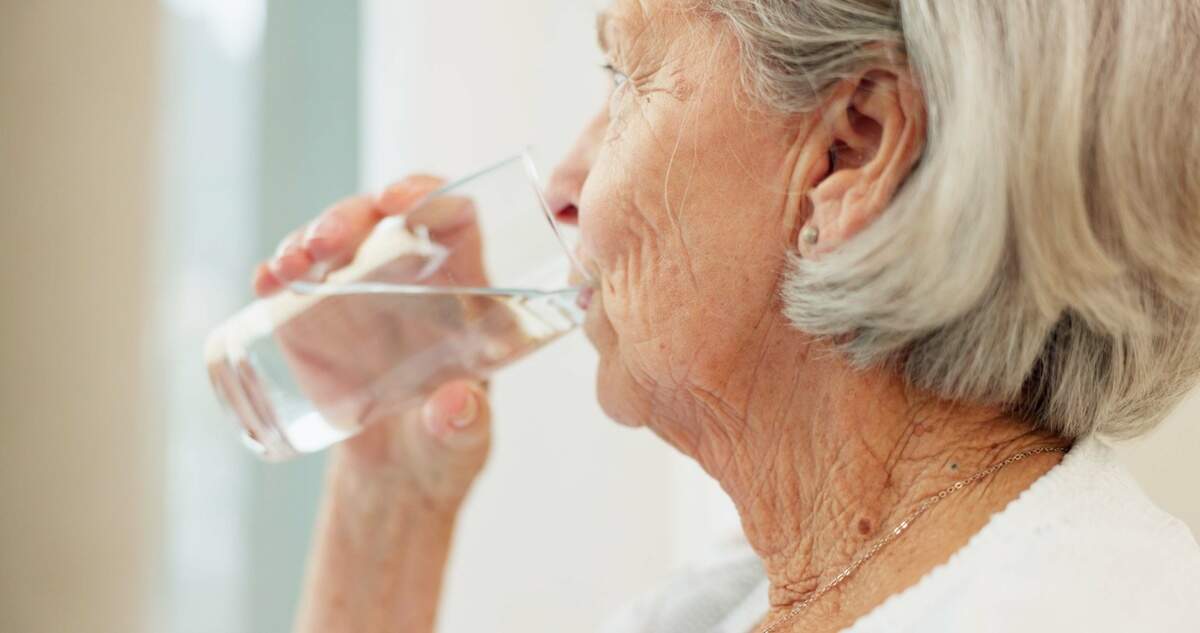 An older woman drinks water