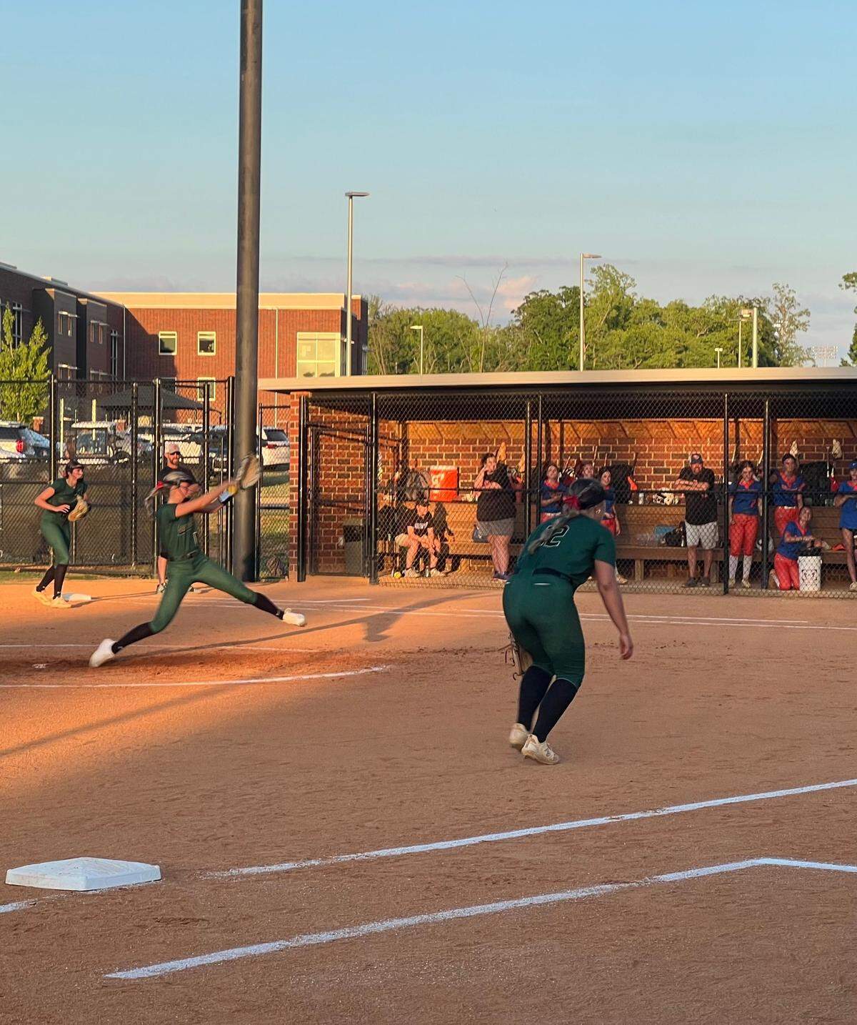 Catawba Ridge starting pitcher Chloe Burger (second green jersey from left) winds up to pitch while third base Audrey Wilson (12, green) creeps up to prepare to cover a bunt attempt.