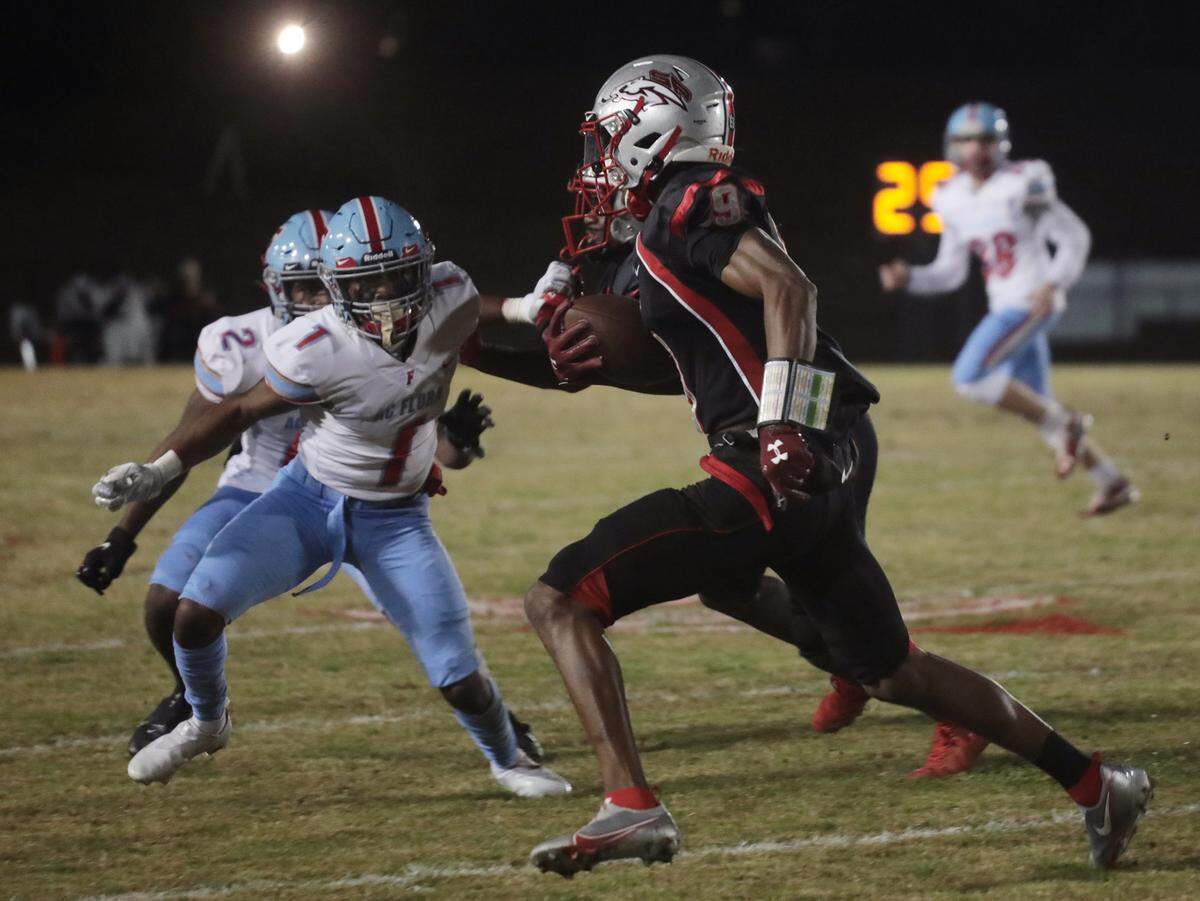 South Pointe’s O’mega Blake carries the ball Friday as he avoids Flora’s Tyler Robinson (1) and Tyrell Green (2).