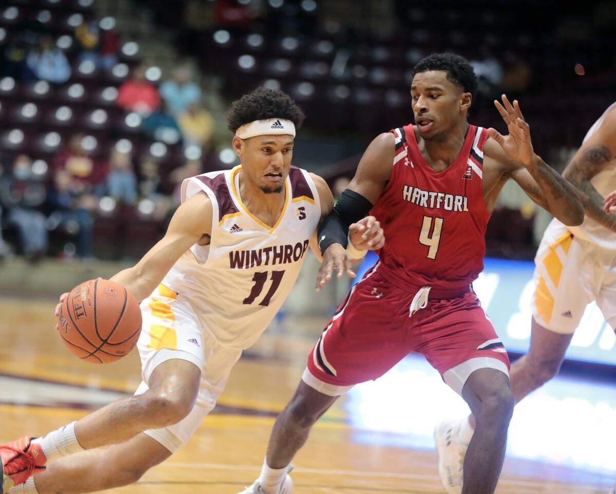 Winthrop’s Drew Buggs heads to the basket around Hartford’s Moses Flowers.