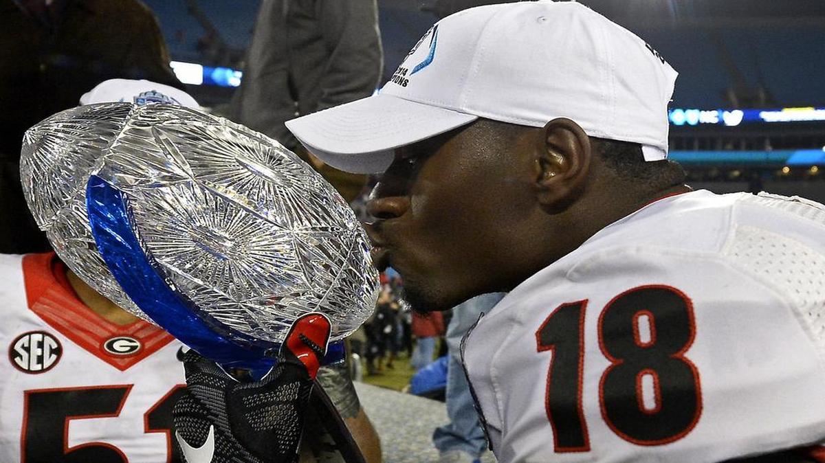 
Georgia Bulldogs split end Jonathon Rumph (18) kisses the championship trophy following the team's victory over the Louisville Cardinals in the Belk Bowl at Bank of America Stadium in Charlotte, NC on Dec. 30, 2014. The Bulldogs defeated the Cardinals 37-14.
