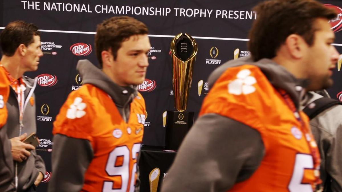 Clemson players walk by the National Championship Trophy as they arrive for Media Day at the Phoenix Convention Center in Phoenix, Ariz., on Saturday.