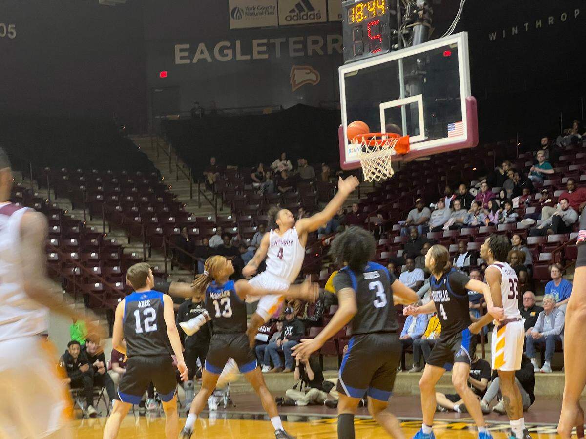 Kelton Talford (white, 4) drives past UNC Asheville forward Nick McMullen (black, 13) for a left-handed layup n the second-half of Winthrop’s 62-60 win over the Bulldogs. Talford led all Eagles with 14 points and nine rebounds.