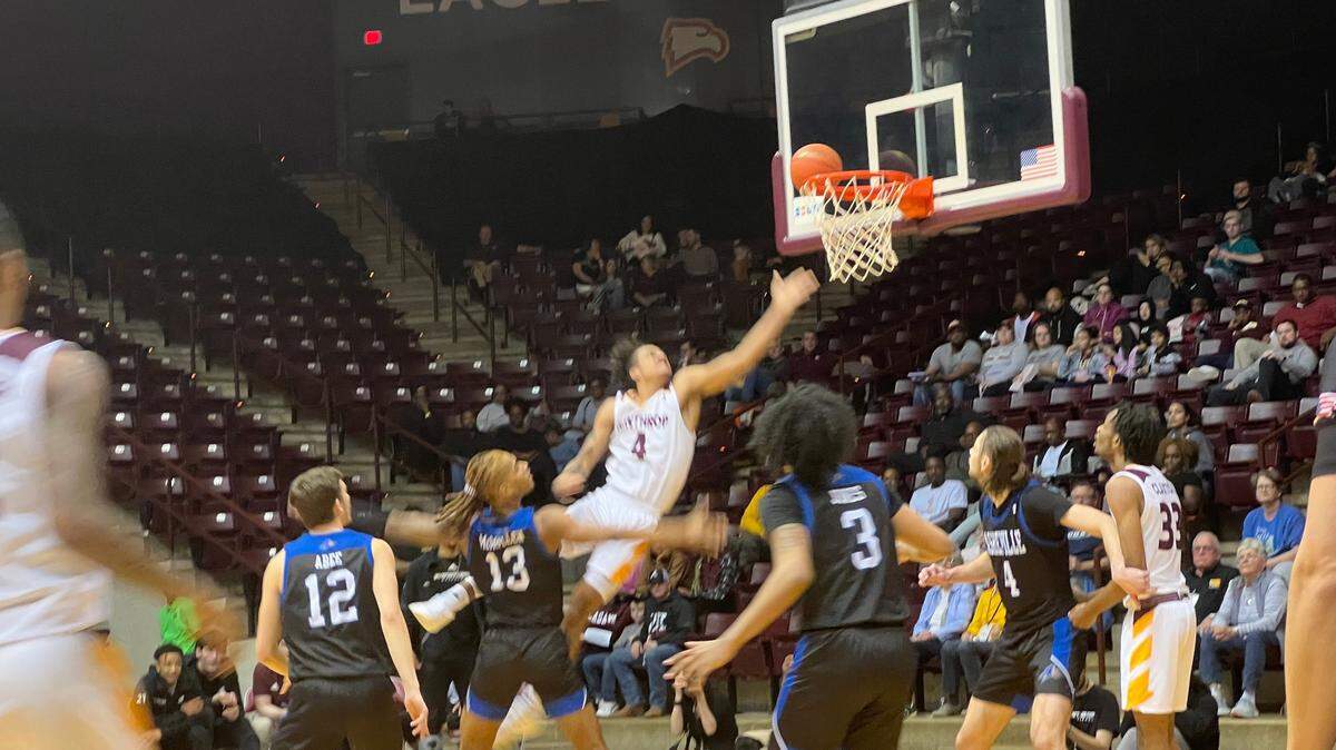 Kelton Talford (white, 4) drives past UNC Asheville forward Nick McMullen (black, 13) for a left-handed layup n the second-half of Winthrop’s 62-60 win over the Bulldogs. Talford led all Eagles with 14 points and nine rebounds.