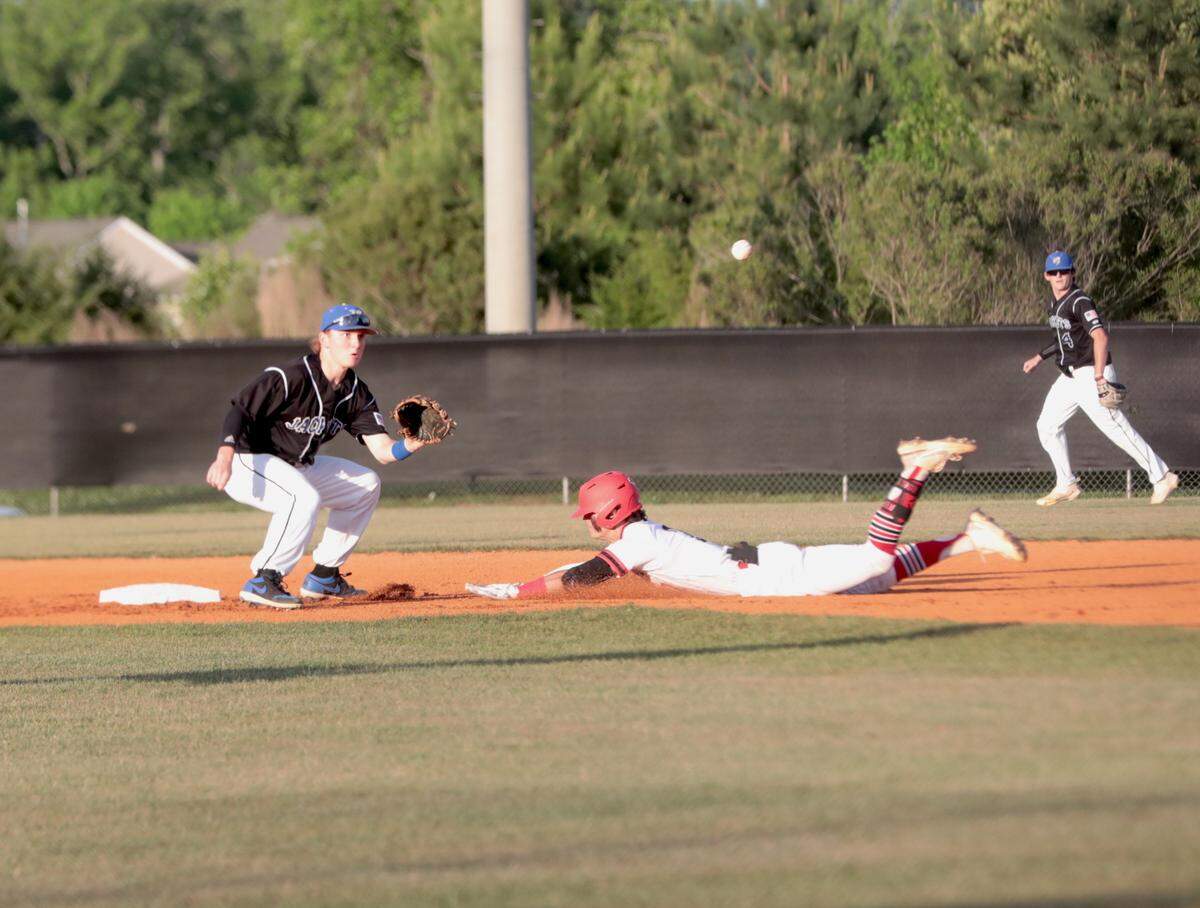 Fort Mill’s Connor Rasmussen misses the ball as Nation Ford’s Kenan Bowman slides into second base.