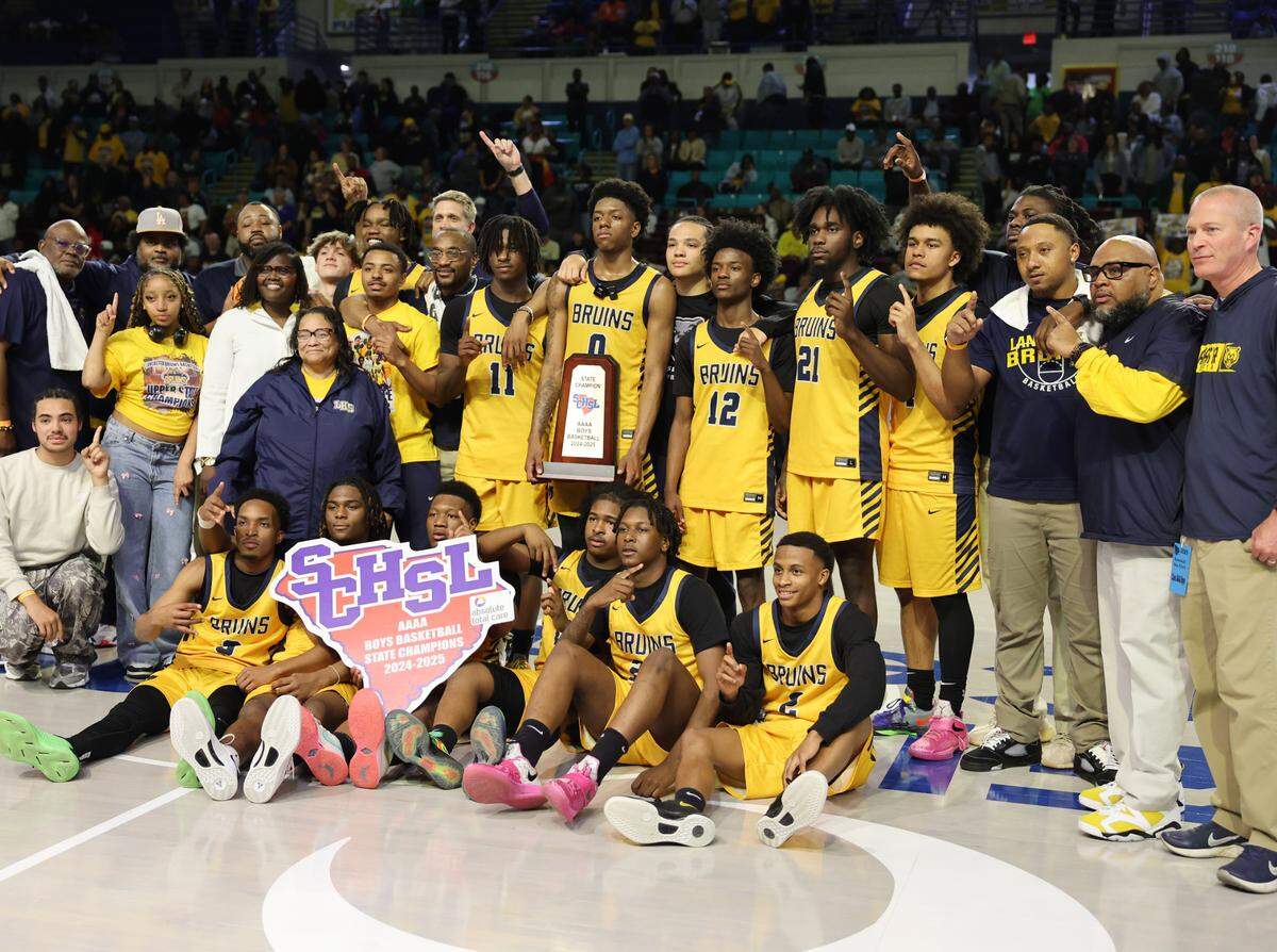 The Lancaster High School boys varsity basketball team pose with their state championship trophy Friday in Florence.