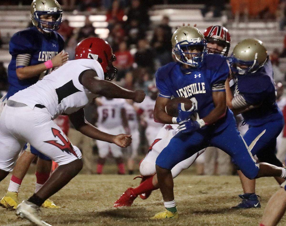 Lewisville’s Deven McCrorey carries the ball against Great Falls’ Natorris Woodard, left, Friday in Richburg.