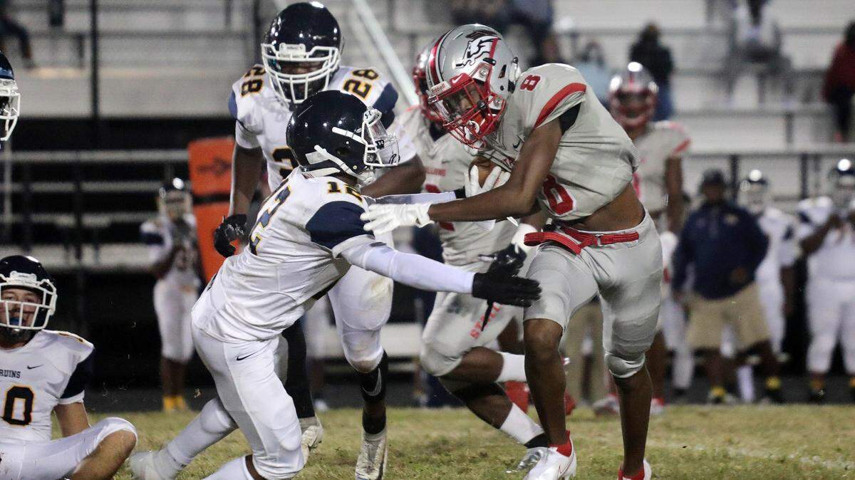 South Pointe’s Jayrin Hemphill (8) is stopped by Lancaster’s Bernard Smith (12) Friday as the Stallions compete with the Bruins in Rock Hill.
