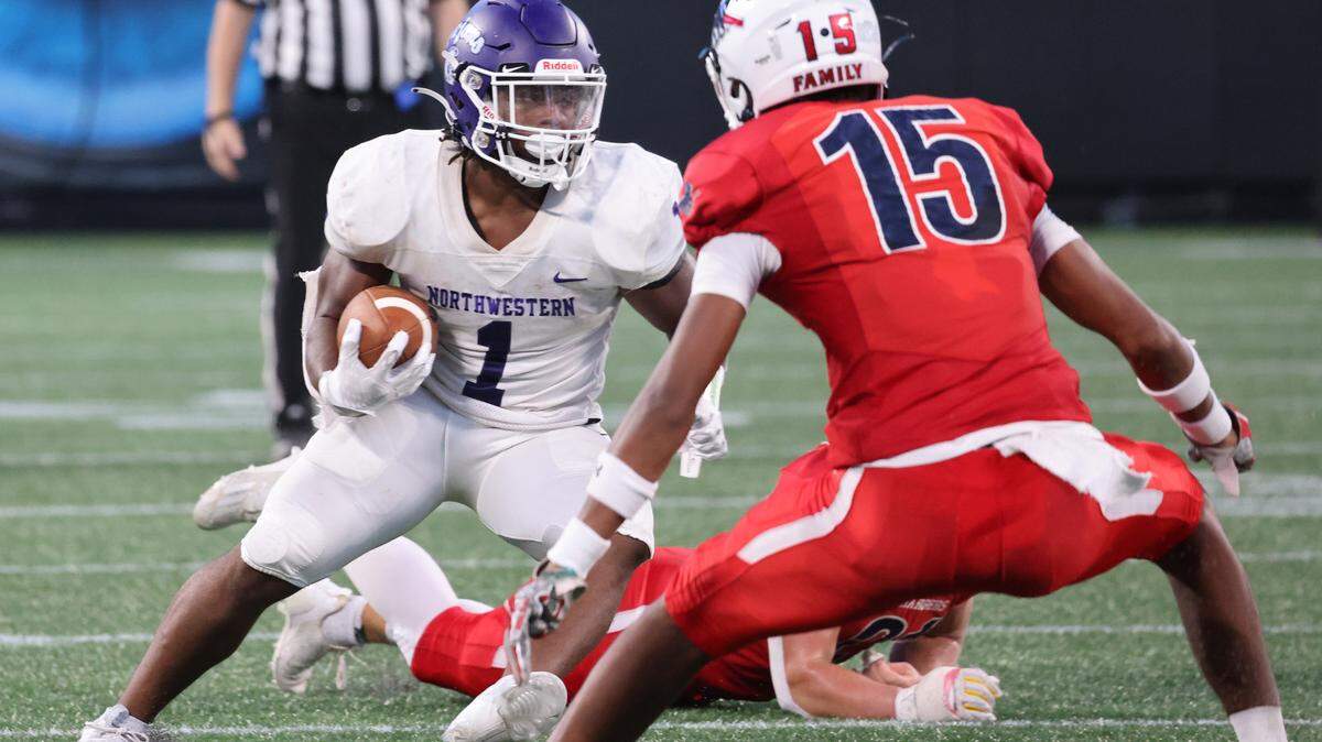 Northwestern’s Turbo Richard carries the ball around Providence Day’s Cairo Skanes on Saturday, Aug. 19, 2023 at Panthers’ Stadium.