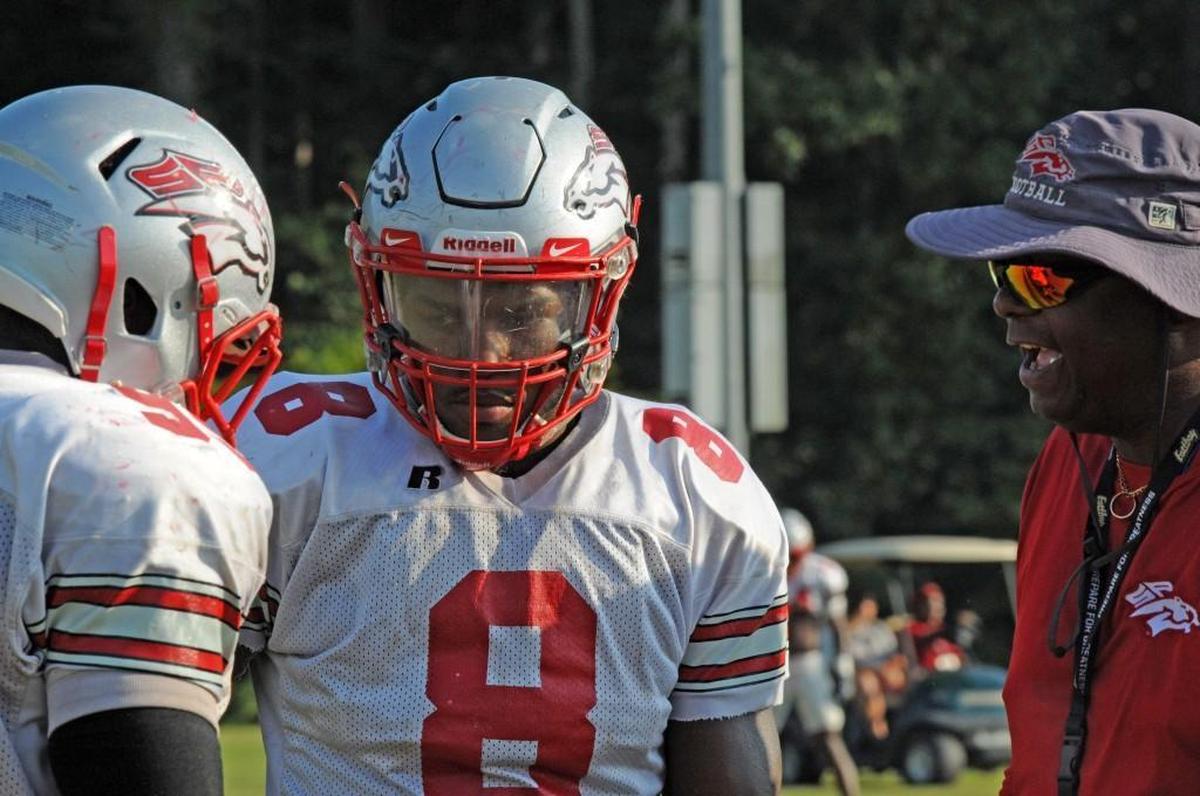 Eli Adams talks with defensive line coach Gerald Peake during Tuesday’s practice. Peake would be hospitalized the following day with stroke-like symptoms.