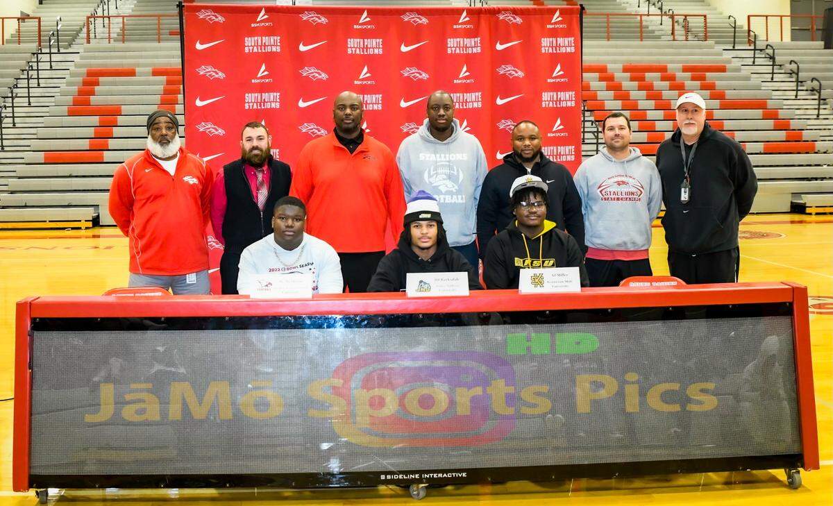 Bobby Collins (third from left) stands with the other coaches as they congratulate the early signees from South Pointe. He says that Barksdale, McMoore and Miller have set the standard for success at South Pointe and is excited to see what next year’s group brings.