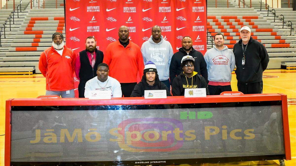 Bobby Collins (third from left) stands with the other coaches as they congratulate the early signees from South Pointe. He says that Barksdale, McMoore and Miller have set the standard for success at South Pointe and is excited to see what next year’s group brings.
