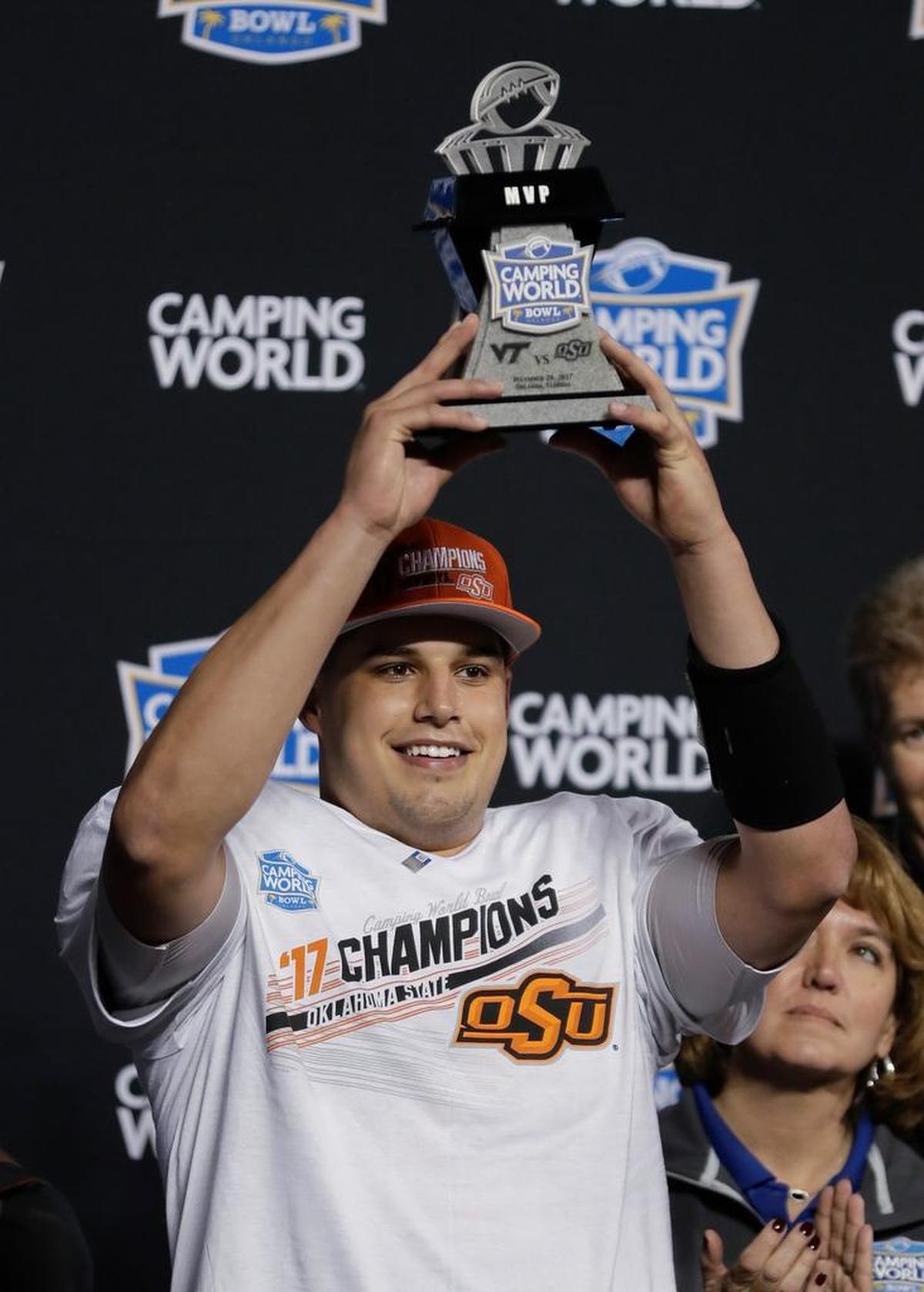 Oklahoma State quarterback Mason Rudolph holds up the MVP trophy after Oklahoma State defeated Virginia Tech 30-21 in the Camping World Bowl NCAA college football game Thursday, Dec. 28, 2017, in Orlando, Fla.