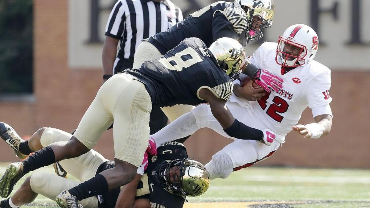 N.C. State quarterback Jacoby Brissett (12) is tackled by Wake Forest's Brandon Chubb (48), Zeek Rodney (top) and Marquel Lee (8) after Brissett ran for yards during the second half of N.C. State's 35-17 victory over Wake Forest at BB&T Field in Winston-Salem, N.C., Saturday, Oct. 24, 2015.