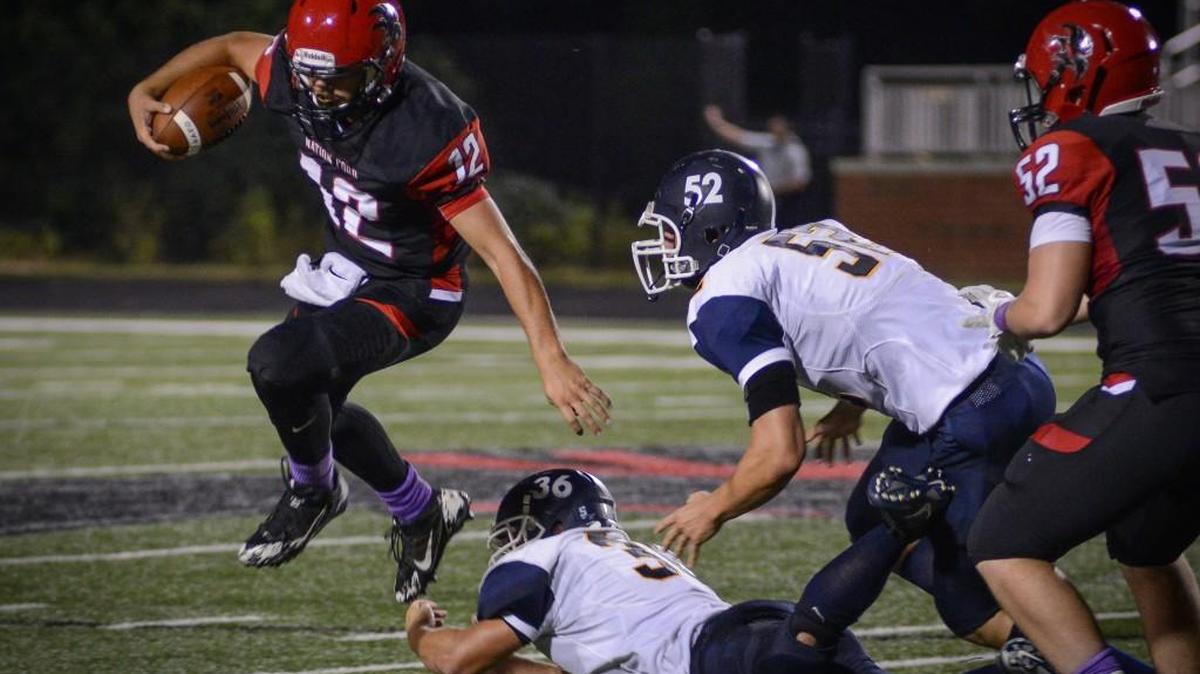 Nation Ford quarterback Kirk Rygol avoids the grasp of two Lancaster defenders during a fourth-quarter run Friday night in Fort Mill.