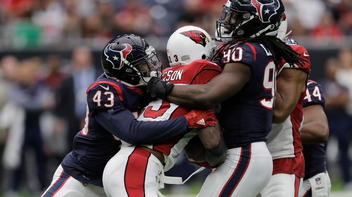 Arizona Cardinals running back Adrian Peterson, center, is wrapped up by Houston Texans defenders Corey Moore (43) and Jadeveon Clowney (90) during the first half of an NFL football game Sunday, Nov. 19, 2017, in Houston.