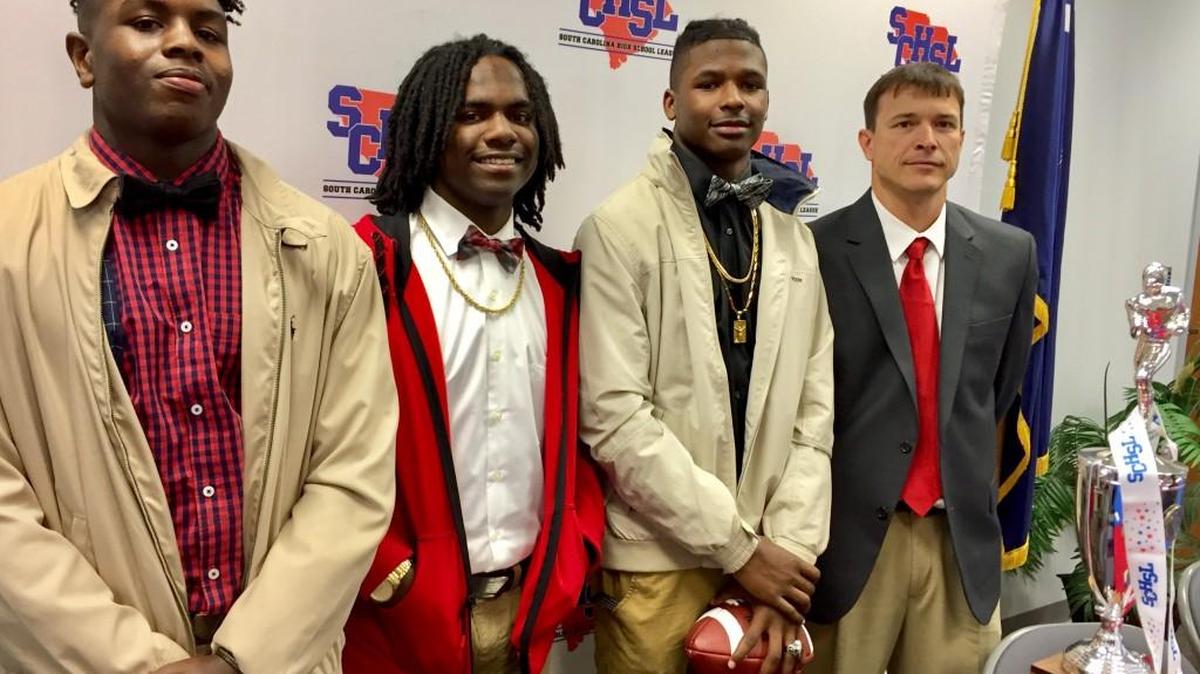 Eyes on the prize: South pointe players Bryson Cooper, Voshon St. Hill and Ken’darius Fredrick, and coach Strait Herron, pose next to the 4A state championship trophy on Monday in Columbia.