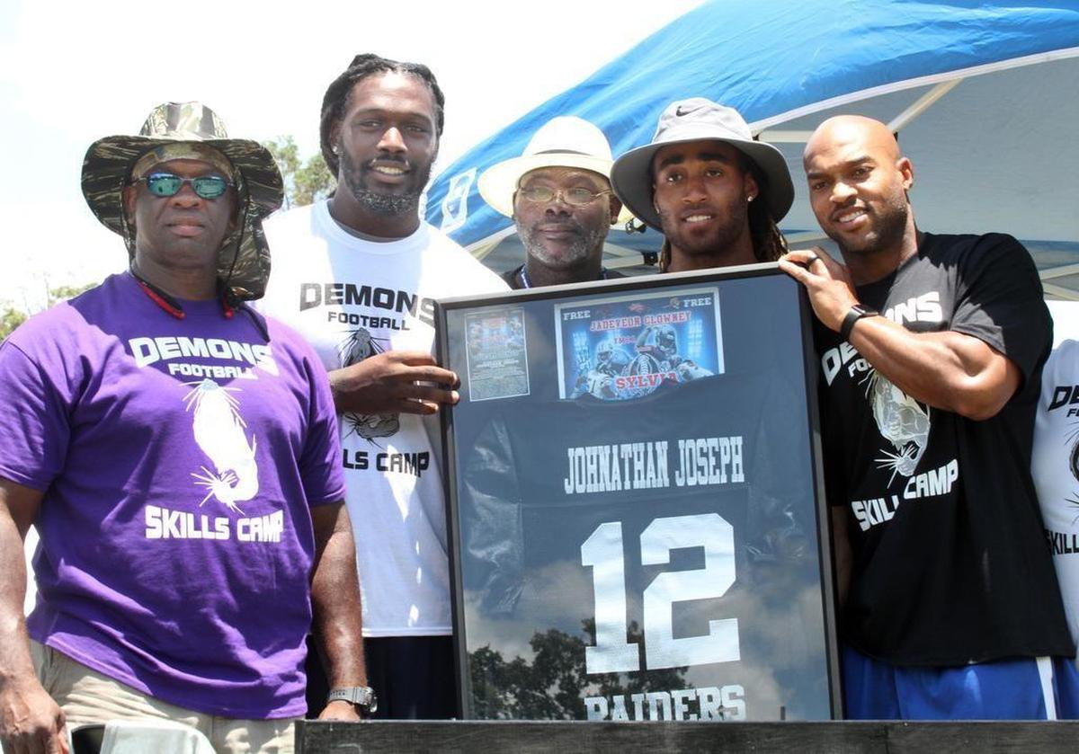 Sylvia Circle Demons Coach Perry Sutton, far left, NFL stars Jadeveon Clowney, second from left, Stephon Gilmore, second from right and Chris Hope, right, and a relative of NFL star Johnathan Joseph, center, pose with Joseph’s retired jersey Saturday at the Sylvia Circle Demons Skills Camp in 2016.