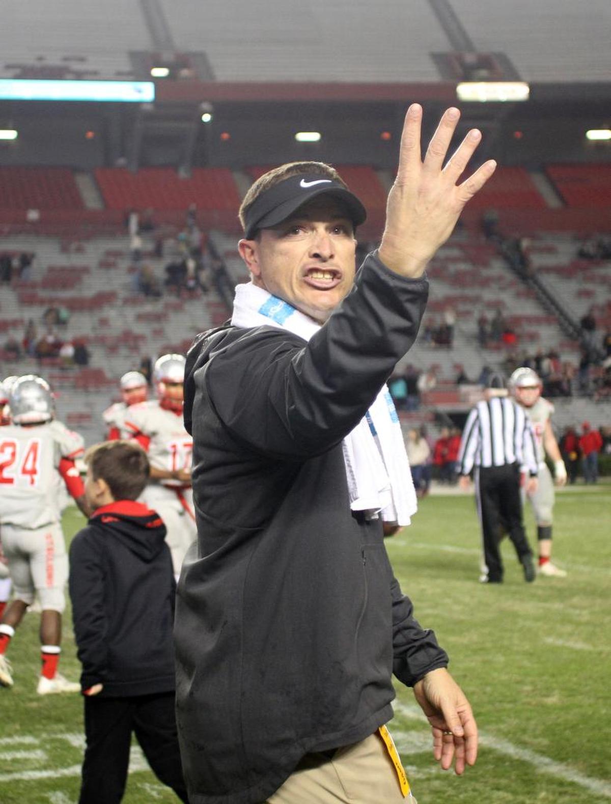 South Pointe High School varsity football coach Strait Herron gestures "four" to the crowd Saturday night after his team won its fourth straight 4A state championship in Columbia.