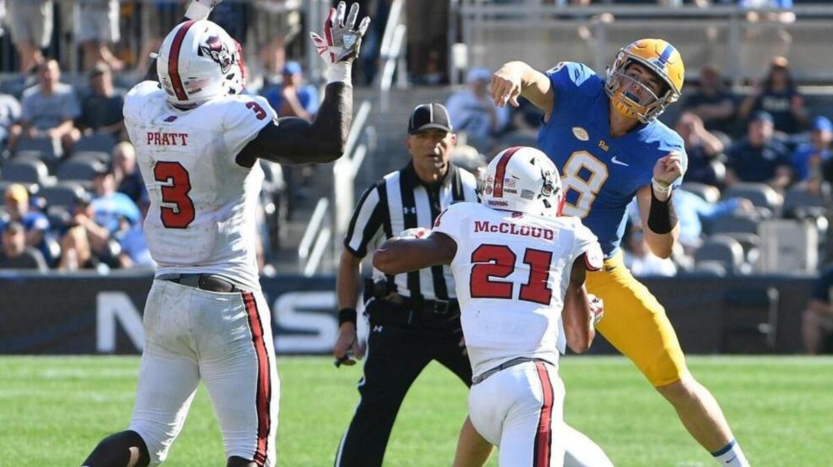 Kenny Pickett of the Pittsburgh Panthers throws a pass under pressure from Germaine Pratt of the North Carolina State Wolfpack and Nick McCloud in the second half during the game at Heinz Field on October 14, 2017 in Pittsburgh, Pennsylvania.