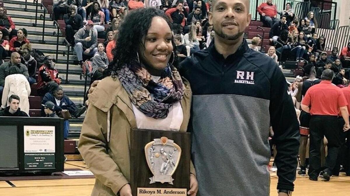 Rock Hill girls’ basketball standout RiKoya Anderson shows off a plaque commemorating her topping the 1,000-career point mark, alongside Bearcats coach Kenny Orr.