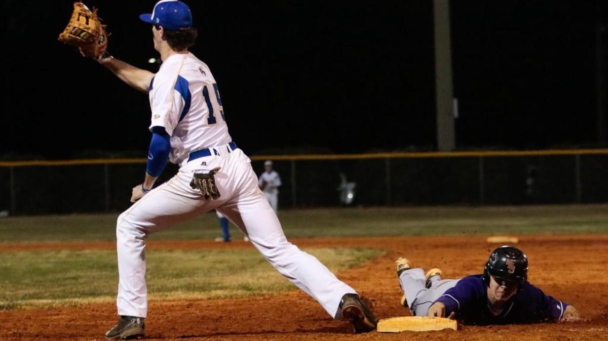 Northwestern’s Will Gardiner slides safely back at first base in the Trojans’ 4-0 win on Tuesday.