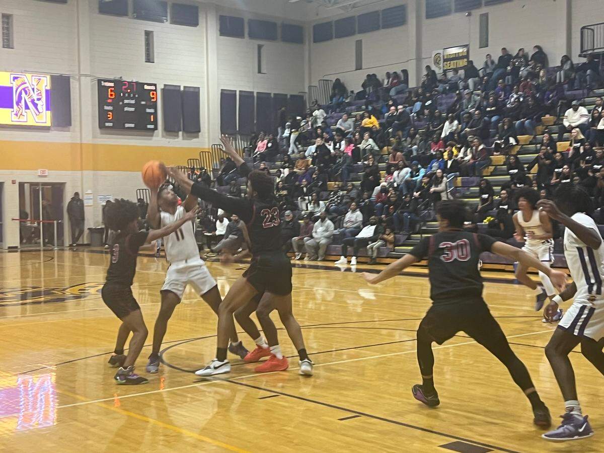 Northwestern’s Jaylan Moore (11, white) banks in a shot at the first-quarter buzzer over multiple Rock Hill defenders in the Trojans’ 46-45 victory over the Bearcats on Jan. 5.